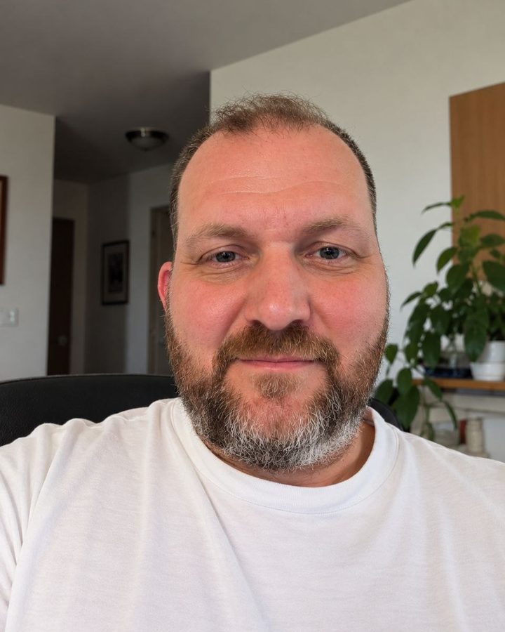 Denis Lunev, owner of Swamp Harrier Painting, smiling in a white T-shirt